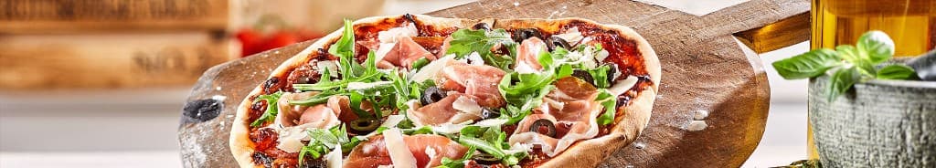 Pizza artisanale sur pelle en bois, jambon cru et roquette
